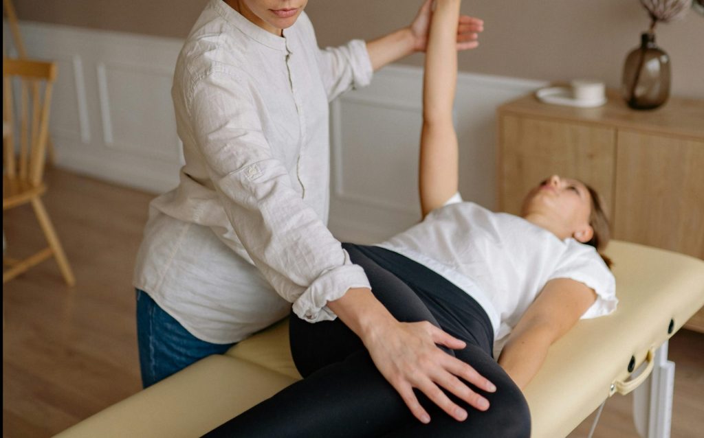 Physiotherapist aids woman with therapeutic exercises indoors.
