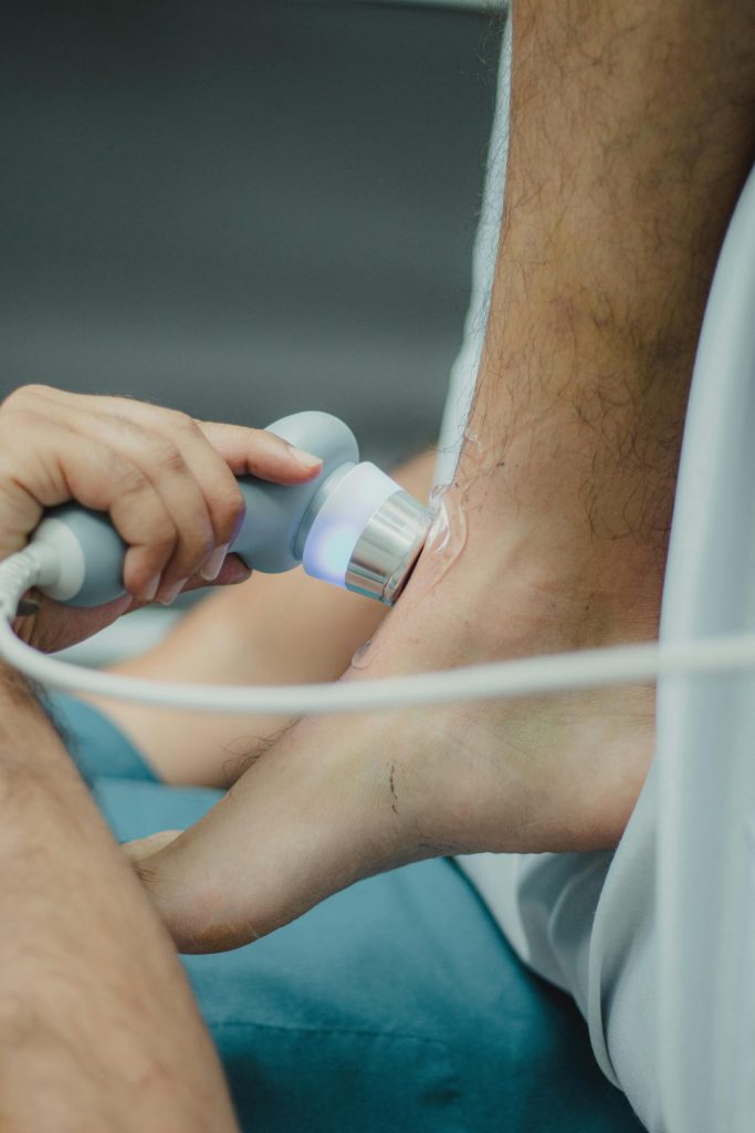 Professional physiotherapist using ultrasound device for leg treatment.